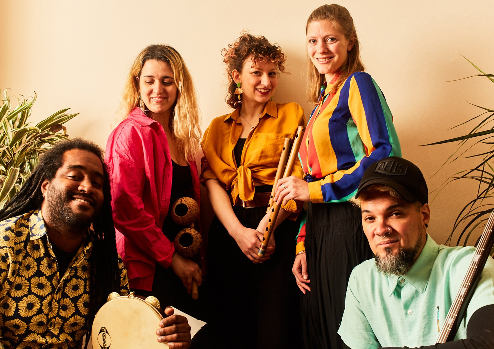 The band members of OLAYÁ band pose in bright clothes with their instruments.