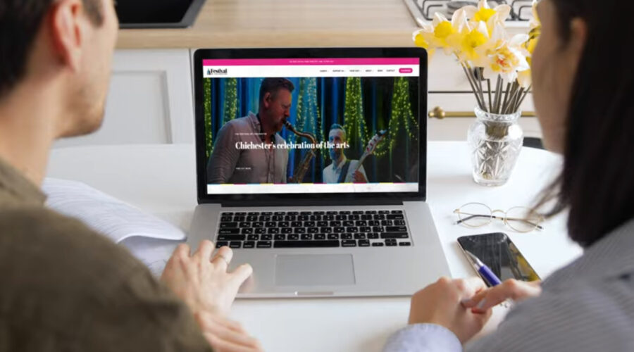 A couple book tickets for Festival of Chichester events on a laptop